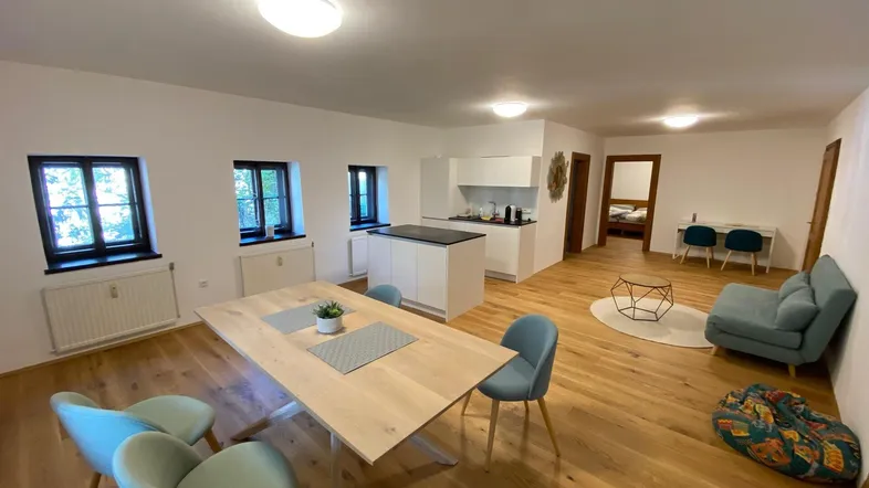 Geräumiger offener Wohn- und Essbereich mit moderner Küche, Holzboden und Blick ins Grüne.