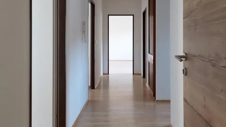 Heller Flur mit Holzboden und mehreren Türen, der zu verschiedenen Räumen führt.