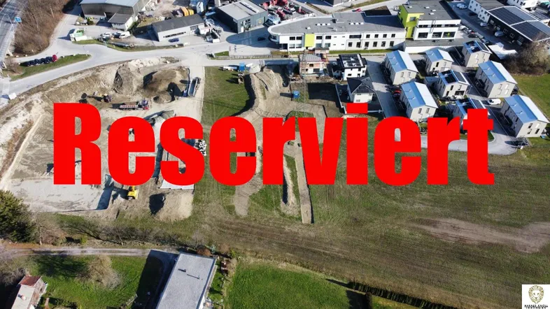 Luftaufnahme eines Baugebiets mit neuen Gebäuden und grüner Umgebung, teilweise noch im Bau.
