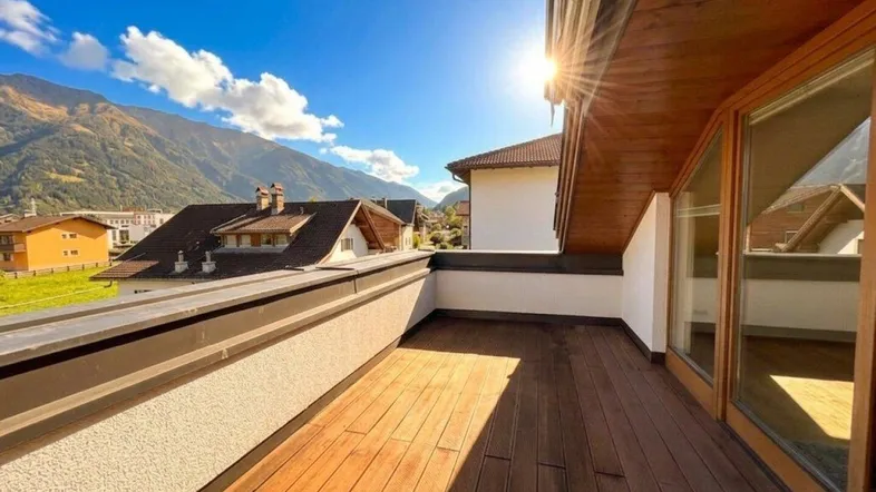 Große Sonnenterrasse mit Holzboden und herrlichem Bergblick unter strahlend blauem Himmel.