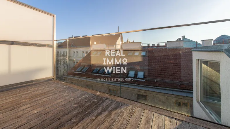 Geräumige Dachterrasse mit Holzboden und Glasgeländer, bietet einen weiten Blick über die Stadt.