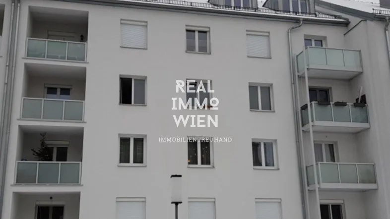 Mehrfamilienhaus mit mehreren Balkonen und Dachgauben in städtischer Umgebung.