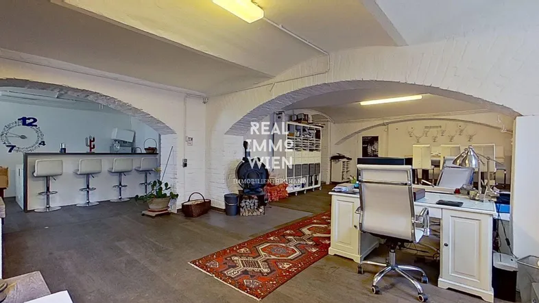 Geräumiger offener Bereich mit gewölbten Decken, einer Bar und einem Arbeitsplatz, ideal für ein kreatives Loftbüro.
