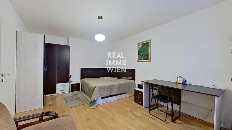 Helles Schlafzimmer mit Holzboden, großem Bett, Kleiderschrank und einem Schreibtisch.