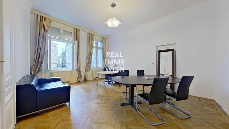 Geräumiges Büro mit Fischgrätparkett, großen Fenstern und einem langen Konferenztisch.