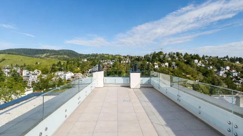 Große Dachterrasse mit Fliesenboden und weitem Blick über die grüne Hügellandschaft.