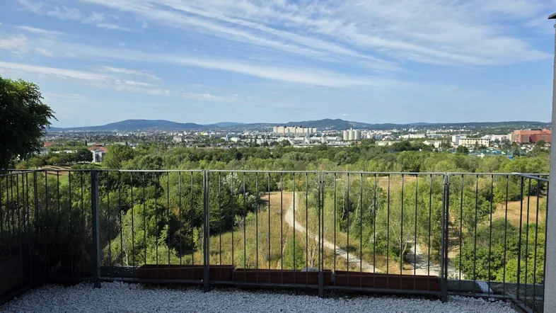 Weitläufige Terrasse mit Kiesboden und Panoramablick über die grüne Landschaft und die Stadt.