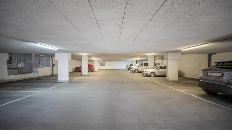 Geräumige Tiefgarage mit mehreren Stellplätzen und guter Beleuchtung für Fahrzeuge.