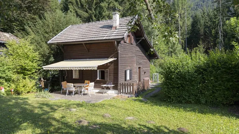 Gemütliches Holzhaus mit Terrasse und Garten in waldreicher Umgebung und Bergblick.