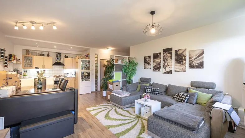 Helles, offenes Wohnzimmer mit integrierter Küche und großem Ecksofa.