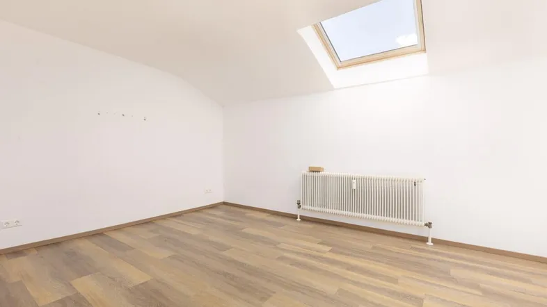 Helles Zimmer mit Dachfenster, Laminatboden und Heizkörper, ideal für Schlaf- oder Arbeitsbereich.