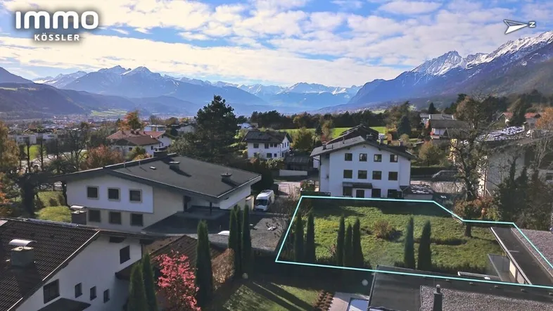 Grundstück mit jungen Bäumen und weitem Blick über die umliegende Wohngegend und Berge.