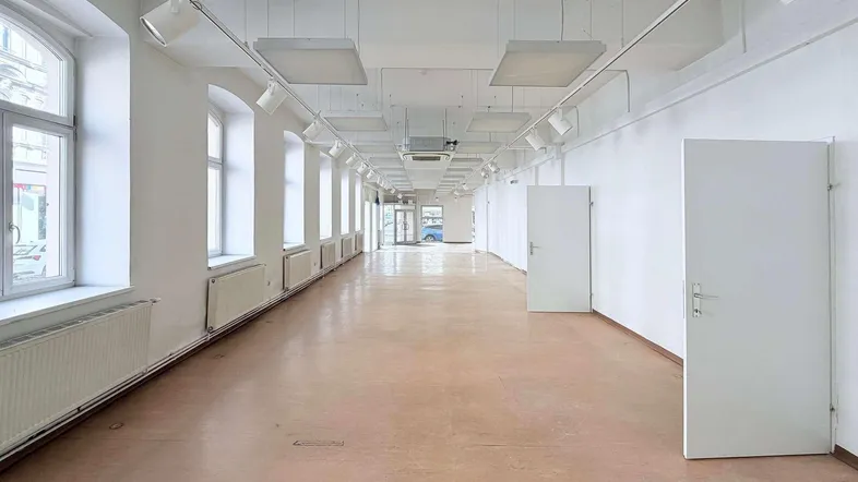 Langer, heller Geschäftsraum mit vielen hohen Fenstern, Schienenbeleuchtung und hohen Decken.