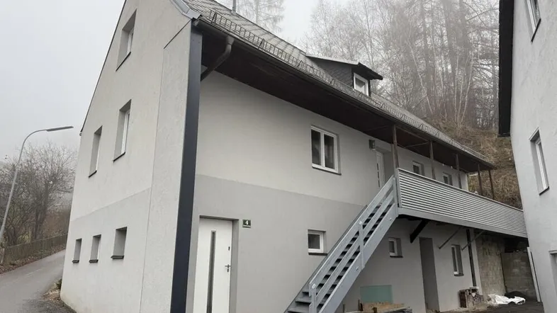 Außenansicht eines modernen Hauses an einem nebligen Tag mit Treppe zum oberen Eingangsbereich.