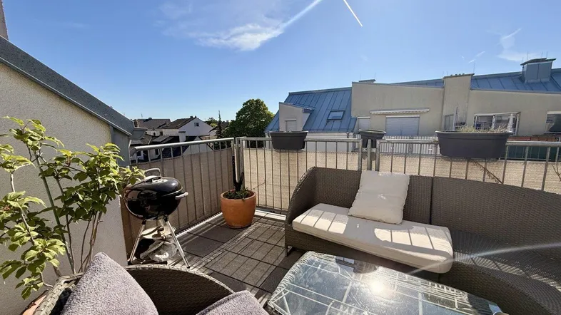 Sonnige Dachterrasse mit bequemen Loungemöbeln und Grill für entspannte Stunden im Freien.
