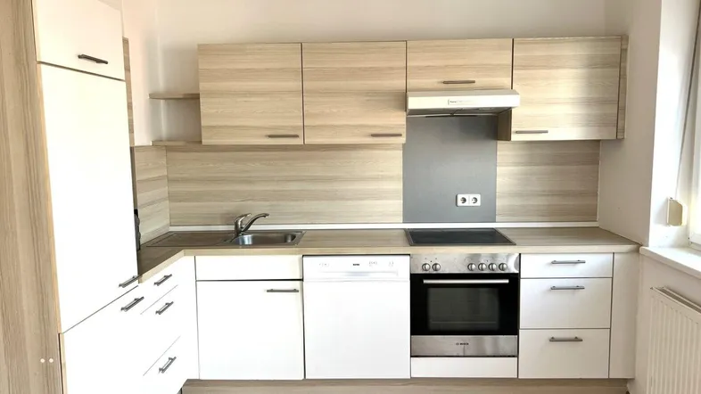 Moderne Einbauküche mit hellen Holzfronten, weißen Unterschränken und integrierten Geräten.