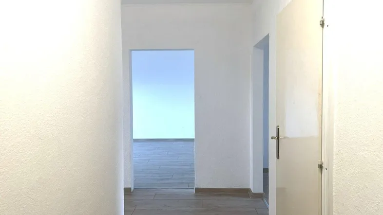 Heller Flur mit modernem Holzfußboden und offenen Durchgängen zu weiteren Räumen.