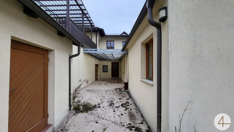 Ein überdachter Gang zwischen zwei Gebäudeteilen mit einfacher Gestaltung und Hofcharakter.