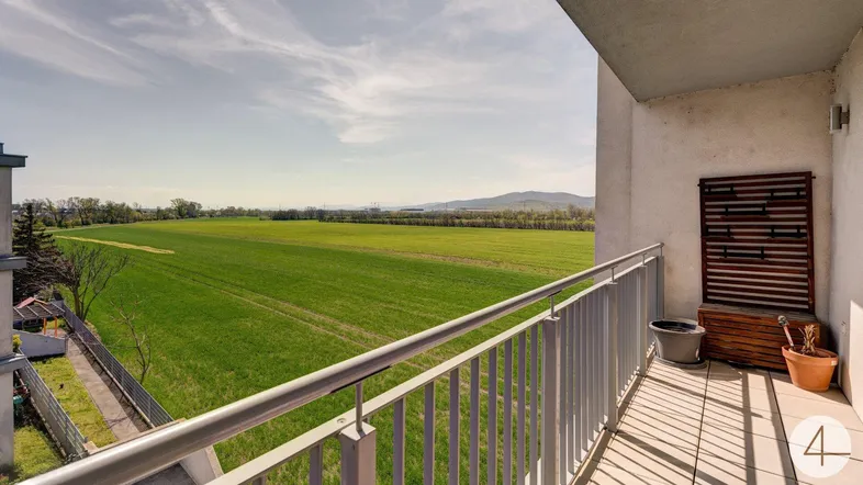 Balkon mit weitem Blick über grüne Felder und sanfte Hügel, perfekt zum Entspannen im Freien.
