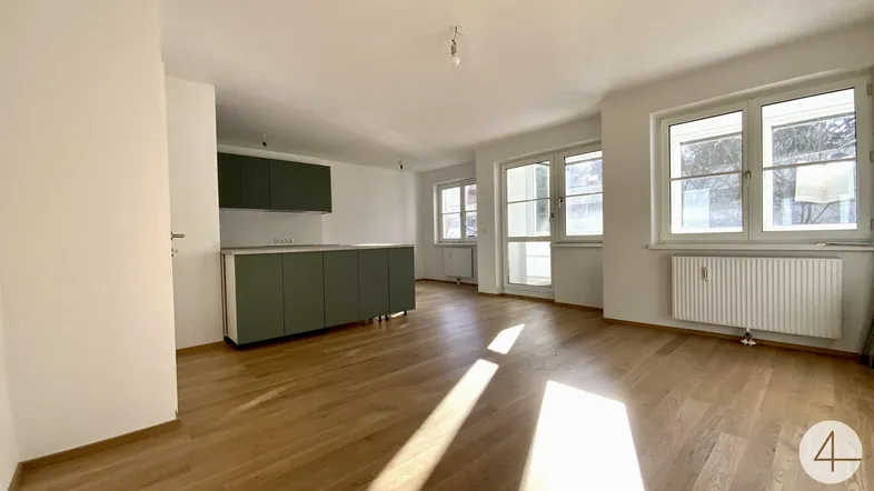 Helles, offenes Wohnzimmer mit integrierter Küche, Eichenparkett und großen Fenstern.