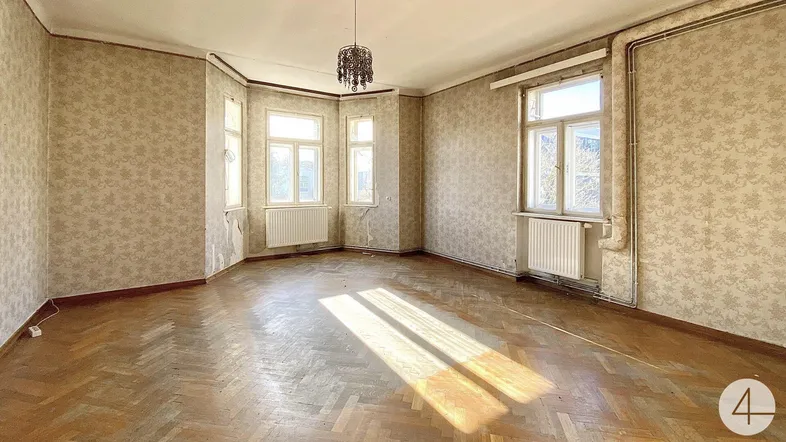 Heller Raum mit Fischgrätparkett, gemusterter Tapete und vielen Fenstern in einem Altbau.