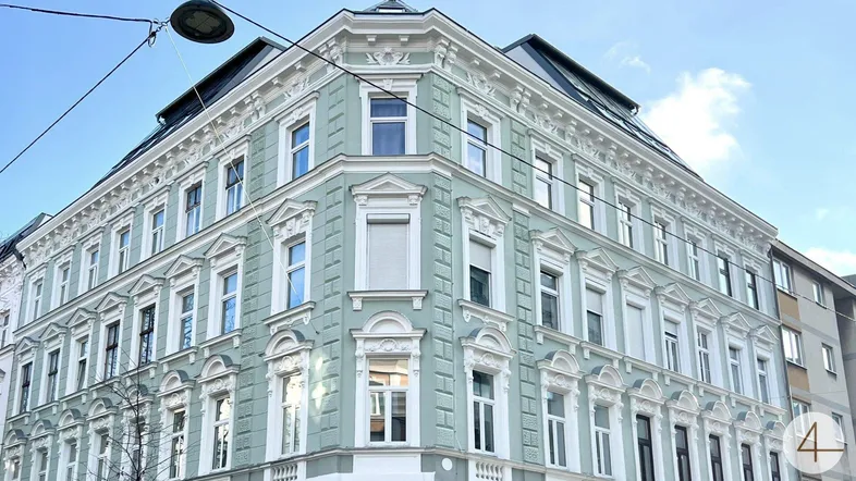 Elegante Eckfassade eines Altbaus mit vielen Fenstern und dekorativen Elementen.