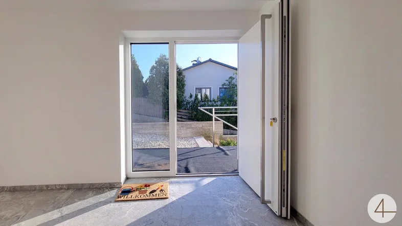 Heller Eingangsbereich mit großer Glastür und Blick auf die gepflegte Außenanlage.