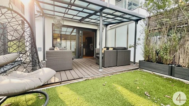 Moderne Terrasse mit Holzboden, gemütlicher Sitzgruppe und angrenzendem Rasenbereich.