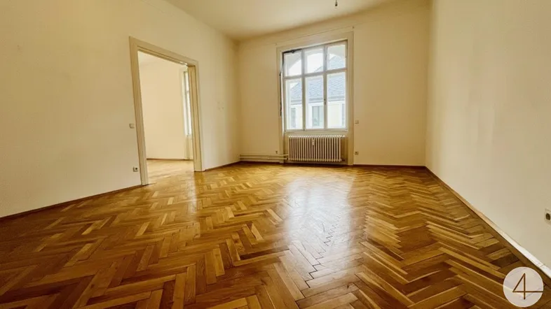 Geräumiges Zimmer mit klassischem Fischgrätparkett und einem großen Fenster.