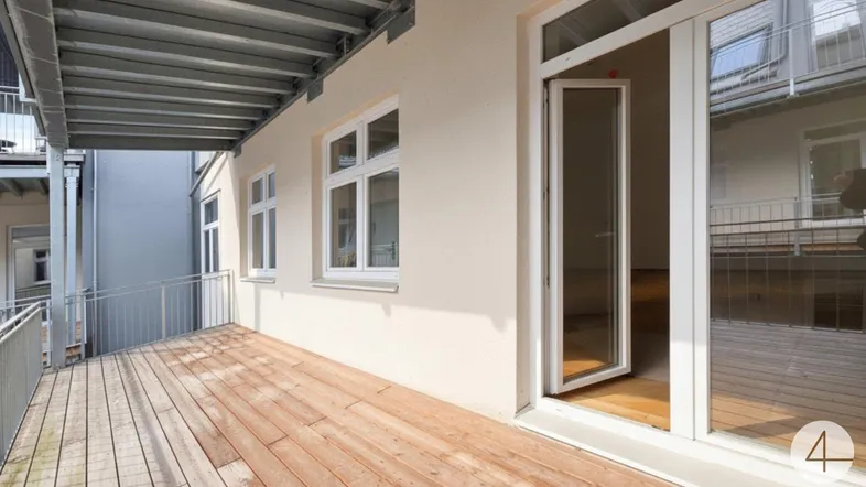 Geräumiger Balkon mit Holzboden und Metallgeländer, ideal für entspannte Stunden im Freien.