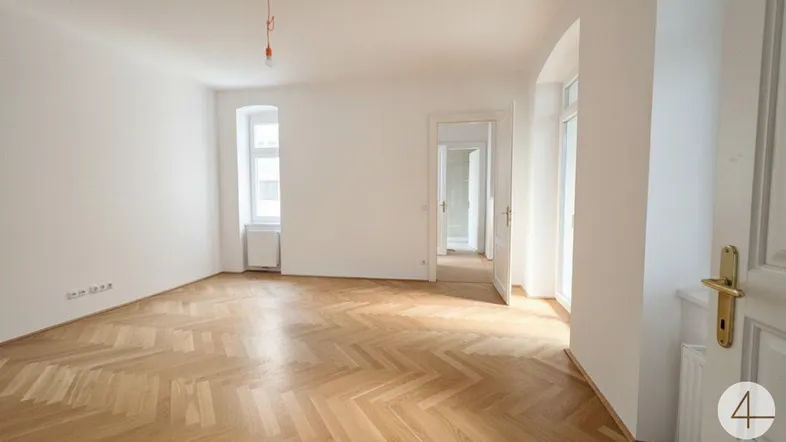 Heller, leerer Raum mit Fischgrätparkettboden und weißen Wänden, bereit zum Einzug.