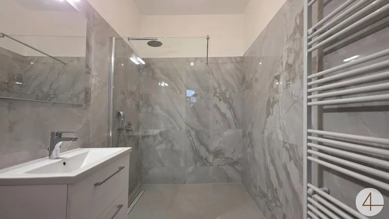 Modernes Badezimmer mit großer begehbarer Dusche, eleganten Fliesen und einem beheizten Handtuchhalter.