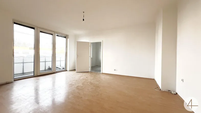 Helles, leeres Wohnzimmer mit großen Fenstern und Zugang zu einem Balkon, bereit für die Gestaltung.