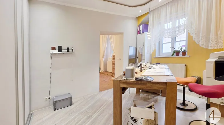Helles Arbeitszimmer mit gelber Akzentwand, Holzschreibtisch und hellem Laminatboden.