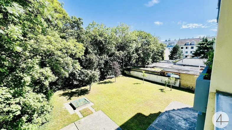 Großer, gepflegter Gemeinschaftsgarten mit Rasenfläche und altem Baumbestand, ideal zum Entspannen im Grünen.