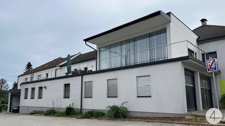Moderne Architektur mit großen Glasflächen und Balkon, umgeben von einer ruhigen Umgebung.
