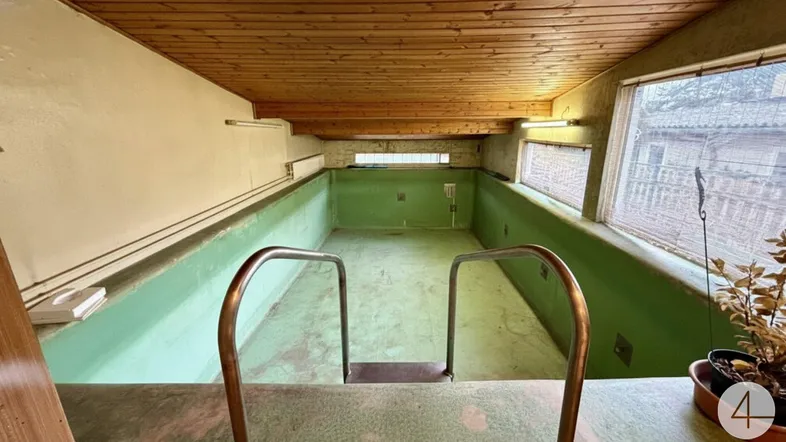 Innenpool mit Holzdecke und leeren Becken, bereit zur Renovierung.