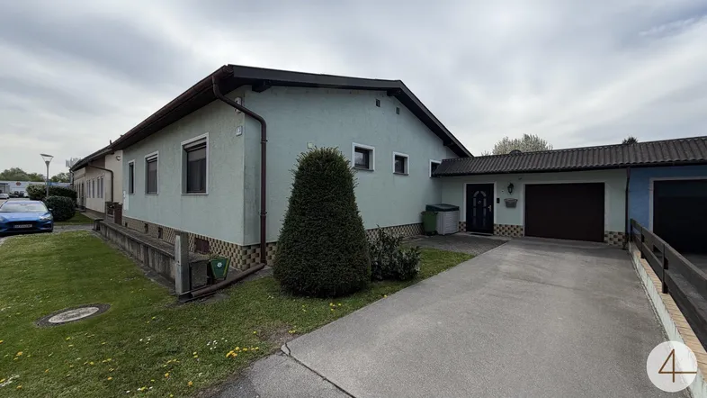 Ansicht des Hauses von der Vorderseite mit Garage und Einfahrt unter bewölktem Himmel.