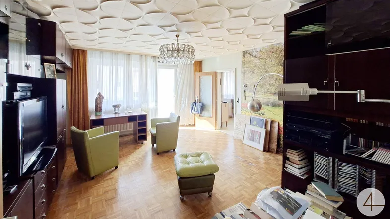 Geräumiges Wohnzimmer mit Parkettboden, dekorativer Decke und Zugang zum Balkon.