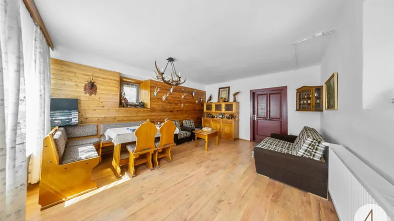 Gemütlicher Wohn- und Essbereich im alpinen Stil mit Holztäfelung und traditionellen Hirschgeweih-Dekorationen.