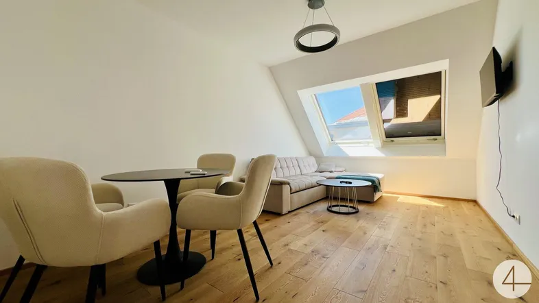 Helles Wohnzimmer mit Holzboden, Dachfenster und gemütlicher Sitzecke unter der Dachschräge.