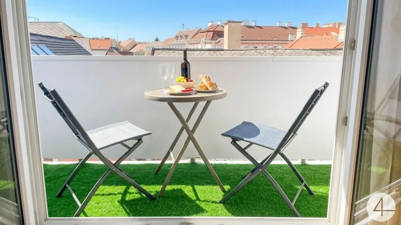 Gemütlicher Balkon mit Kunstrasen, kleinem Tisch und Stühlen, ideal für entspannte Stunden im Freien.