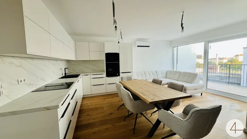 Moderne offene Wohnküche mit weißen Schränken, Holzboden und Zugang zu einer großen Terrasse.