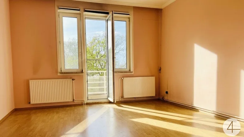 Helles Wohnzimmer mit Holzfußboden, rosa Wänden und Zugang zu einem Balkon oder Außenbereich.