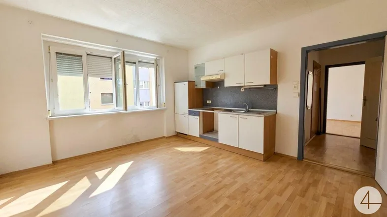 Helles Wohnzimmer mit integrierter Küchenzeile, Laminatboden und Blick ins Grüne.