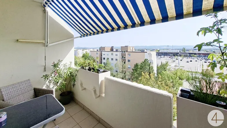 Gemütlicher Balkon mit Markise, Sitzgelegenheiten und weitem Blick über die Stadt.