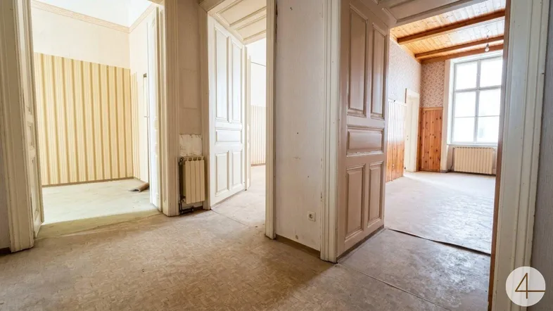 Blick durch mehrere Türöffnungen in verschiedene Räume mit alten Tapeten und Holzdecken.
