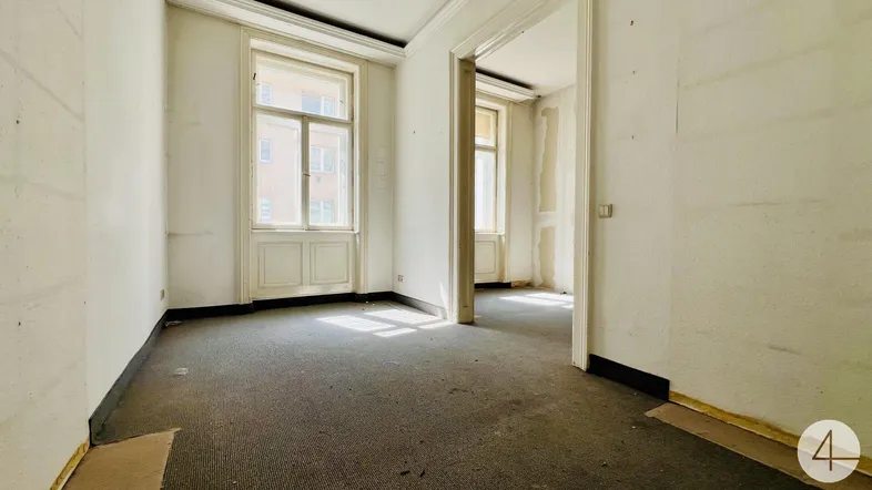 Leerer Raum mit Teppichboden und großen Fenstern, bereit für Renovierung und Neugestaltung.