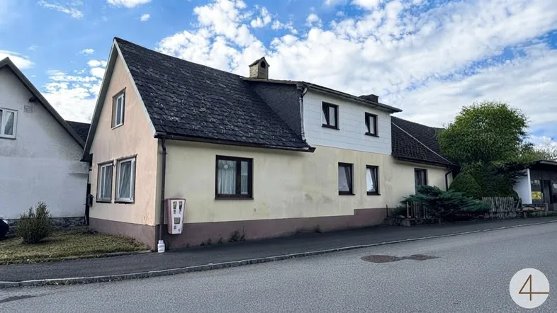 Altes Wohnhaus mit Satteldach und heller Fassade, direkt an der Straße gelegen.