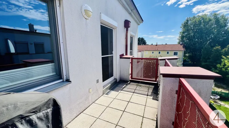 Heller Balkon mit Fliesenboden und rotem Geländer, bietet Blick auf die Umgebung.